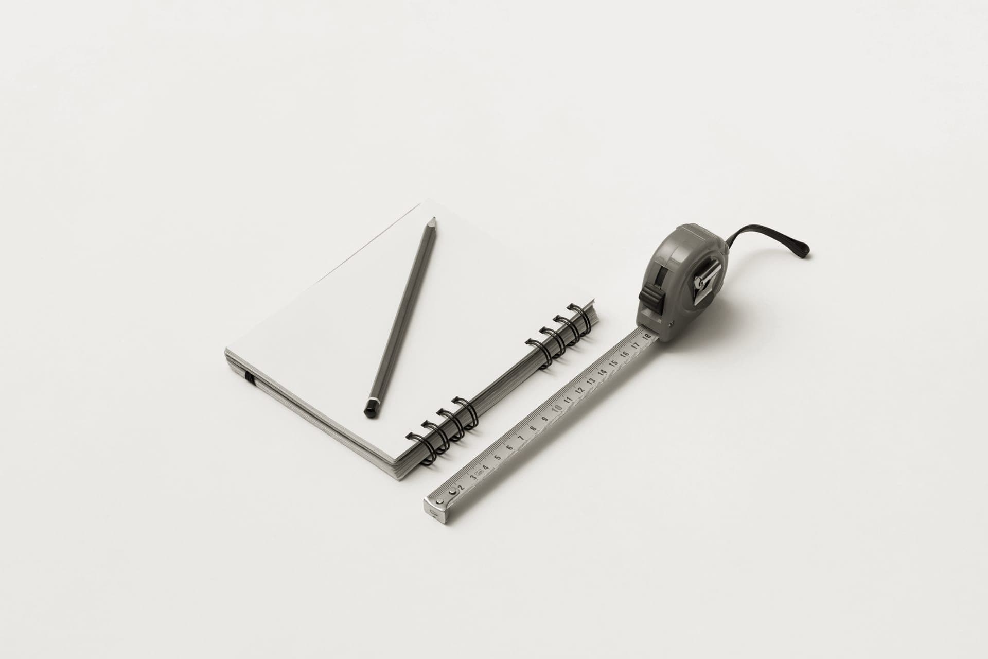 Notebook, pencil and measuring tape on a wooden desk